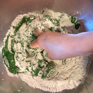 hand mixing spinach puree into the flour