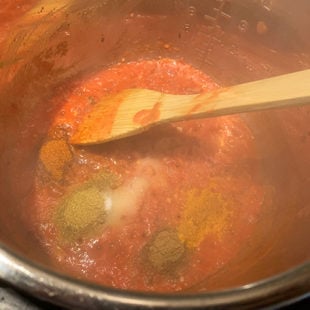 pureed tomatoes with spices in a steel pot