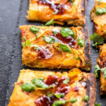three slices of pizza topped with cilantro and chutney and placed on a black board