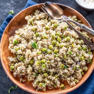 plate of quinoa with green peas and a bowl of yogurt placed in the background