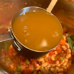 broth being added to a pot of soup