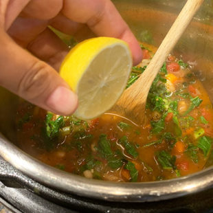 lemon juice being squeezed into a bowl of soup