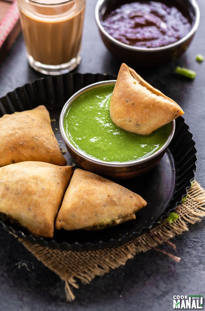 samosa dipped in a bowl of cilantro chutney