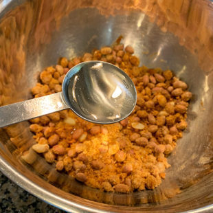water being added to a bowl of peanuts and spices