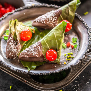 3 chocolate paan topped with cherries and placed in a antique plate