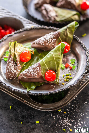 3 chocolate paan topped with cherries and placed in a antique plate