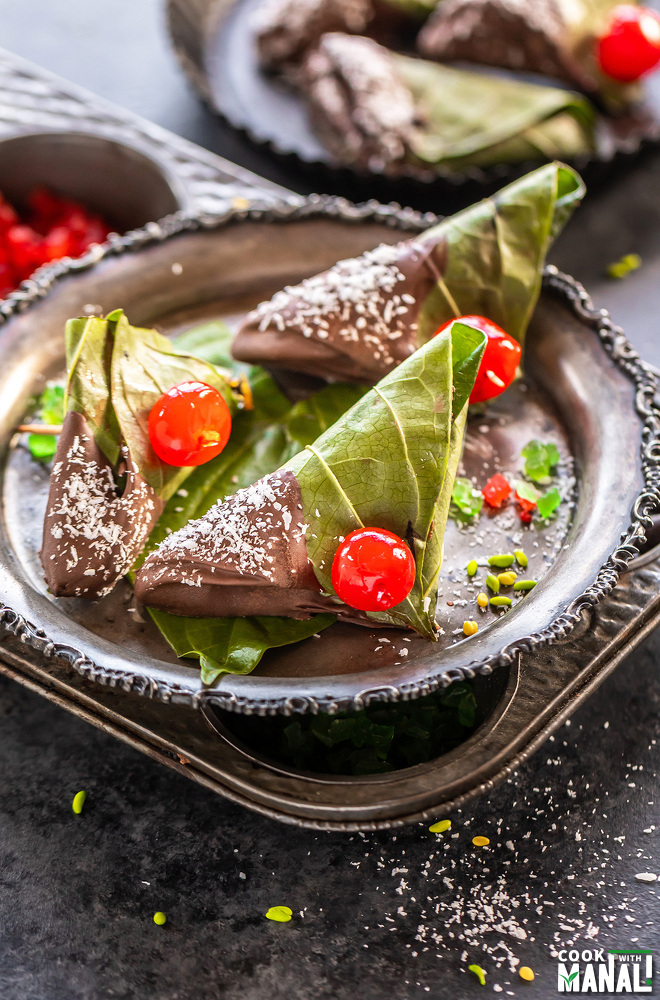 3 chocolate paan topped with cherries and placed in a antique plate