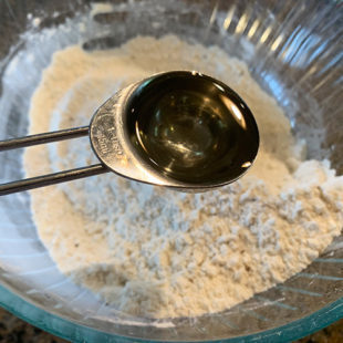 oil being added to a bowl of flour
