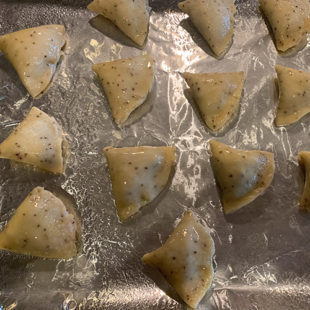 filled samosa arranged on a baking sheet lined with aluminum foil
