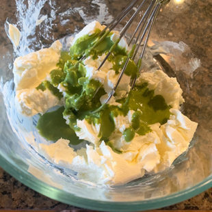cream cheese in a bowl with cilantro chutney drizzled on top