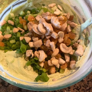 cashews, raisins, green onions added to a bowl of cream cheese