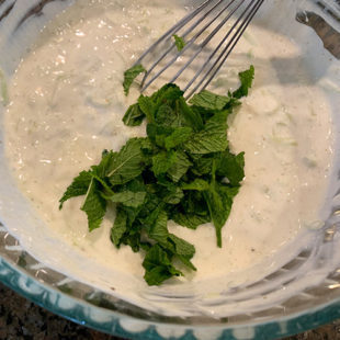 mint leaves added to a bowl of yogurt