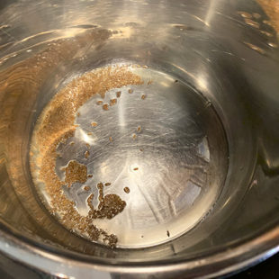 cumin seeds in oil in a pot