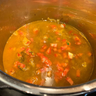 water with spices, lentils, tomatoes in a pot