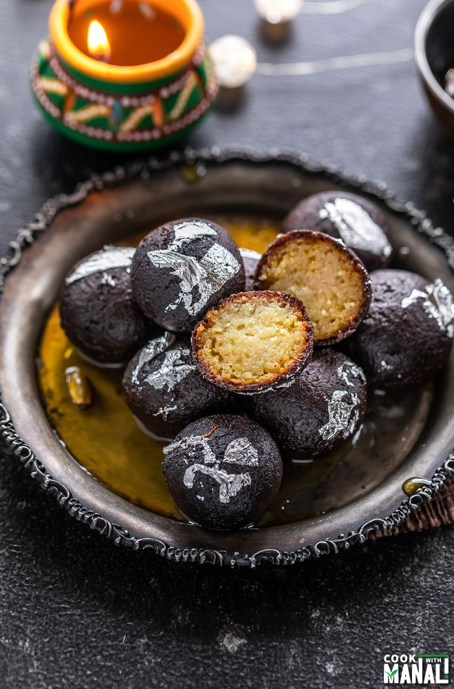 plate of kala jamun with one jamun cut to show the interior