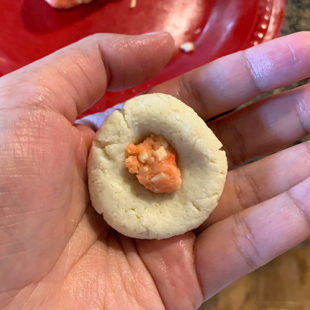 a small dough ball placed on a hand and an orange color stuffing inside the dough