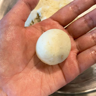 a round smooth dough ball placed on a hand