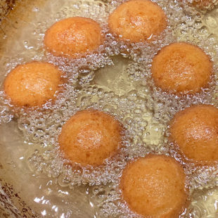 brown color dough balls fried being fried in hot oil