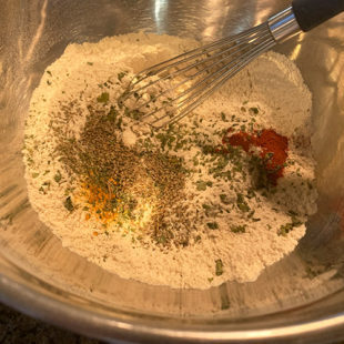 flour with spices in a bowl with a whisk
