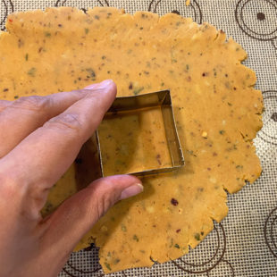 square cookie cutter cutting cookies out of a dough