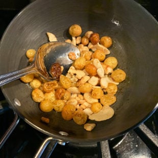 raisins and cashews being cooked in a pan