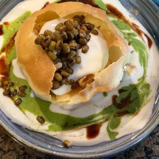 crisp fried ball of dough crushed open and filled with yogurt, lentils