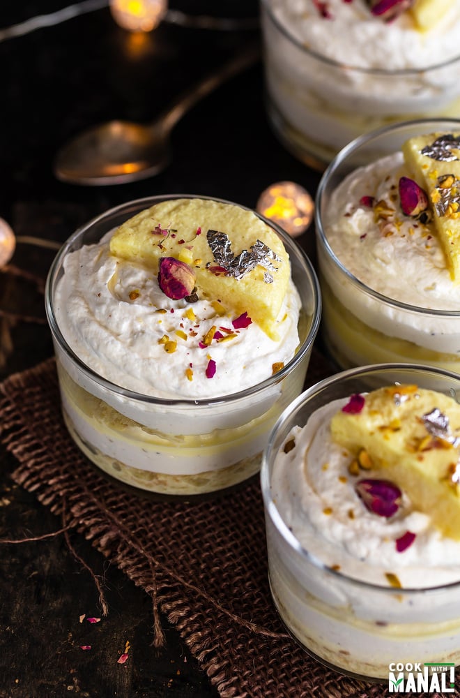 4 rasmalai cake jars placed on a board with lights in the background