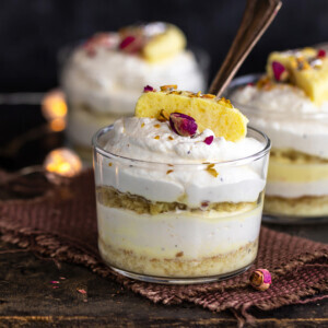 3 rasmalai cake jars placed on a board with lights in the background