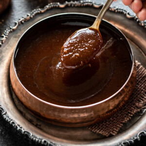 spoon inside a bowl of tamarind chutney served in a copper bowl