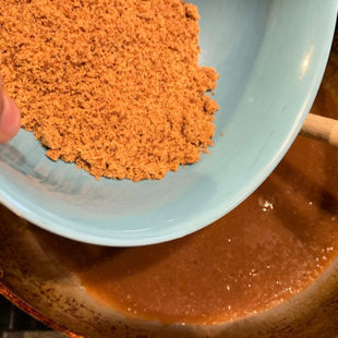 jaggery powder being added to a kadai