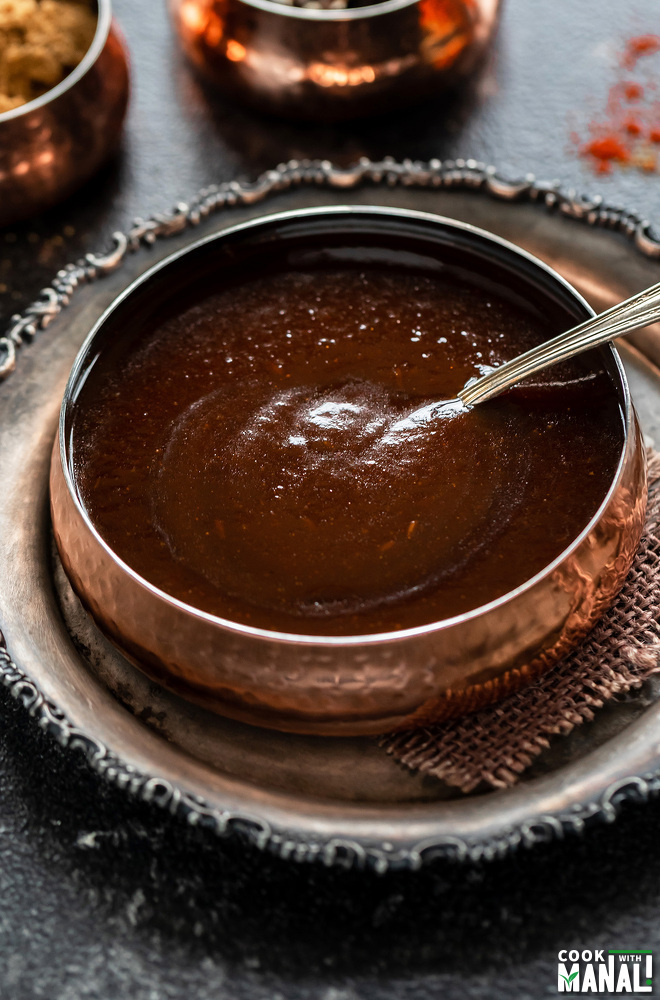 tamarind chutney in a copper bowl with a spoon