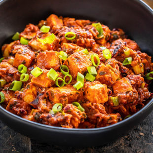bowl of spiced paneer topped with green onions