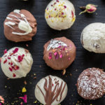 burfi truffles topped with nuts, rose petals arranged on a black board