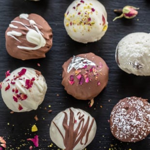 burfi truffles topped with nuts, rose petals arranged on a black board