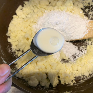 milk being added to a pan with milk powder and sugar