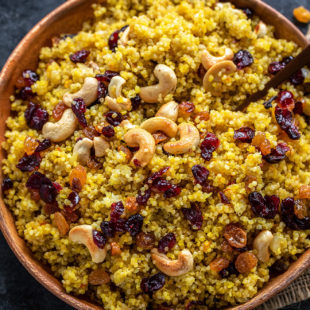 plate of saffron quinoa topped with roasted cashews, raisins and cranberries