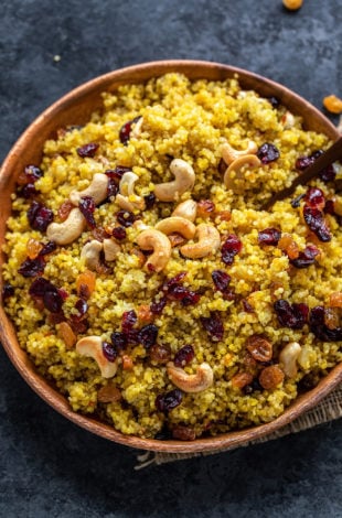 plate of saffron quinoa topped with roasted cashews, raisins and cranberries