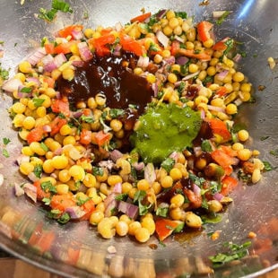 bowl of white peas mixed with onions, tomatoes, spices and topped with chutneys