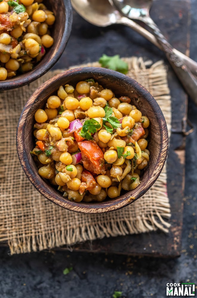 bowl of matar chaat topped with cilantro and 2 spoons placed on the side