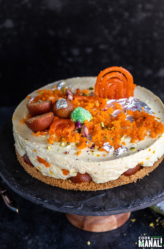 a cheesecake topped with Indian sweets like jalebi, gulab jamun