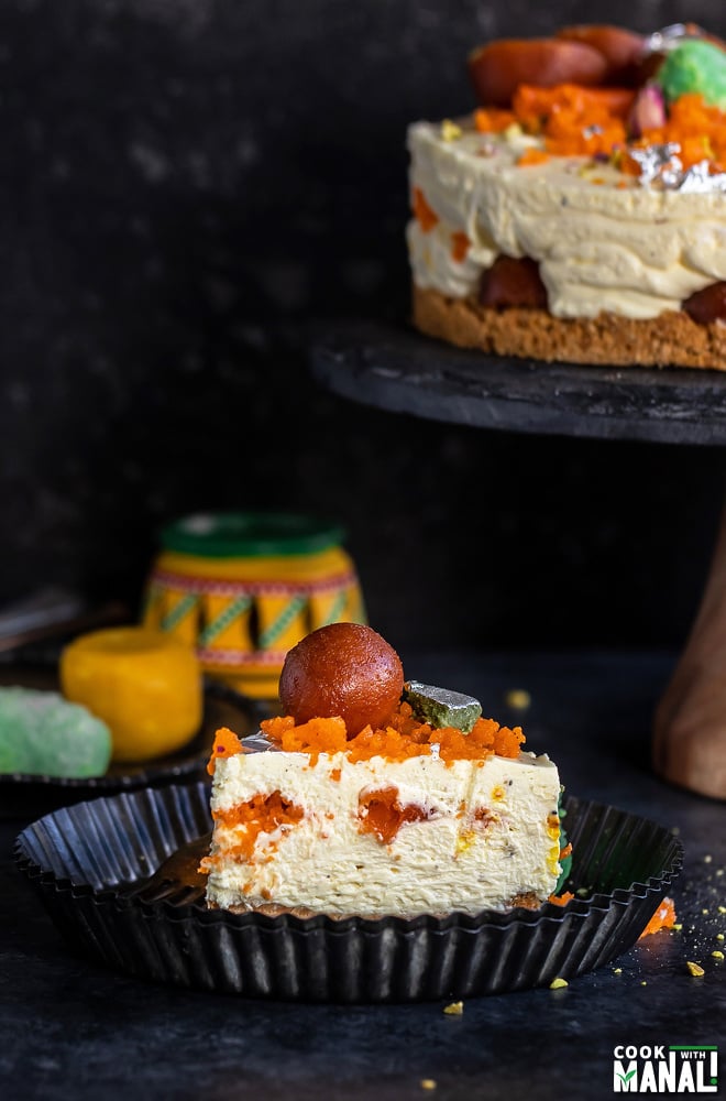 slice of mithai cheesecake with the full cheesecake placed in the background