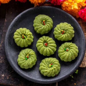 7 paan peda arranged on a plate with string of flower on the side