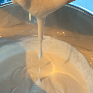 batter dripping off from hand to show the consistency of the batter
