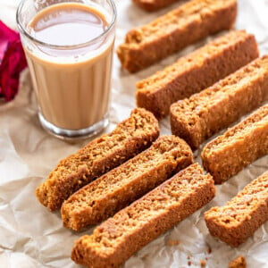 some rusk arranged on a tray with chai glasses in the background