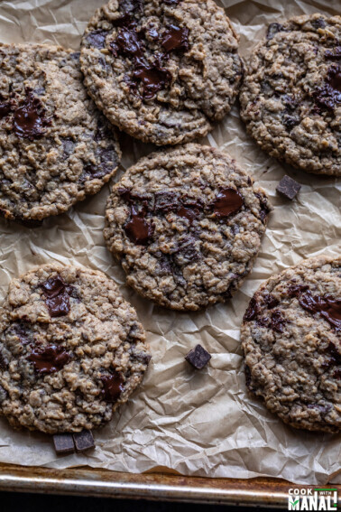 eggless oatmeal chocolate chunk cookies arranged on top of a parchment paper on a baking tray