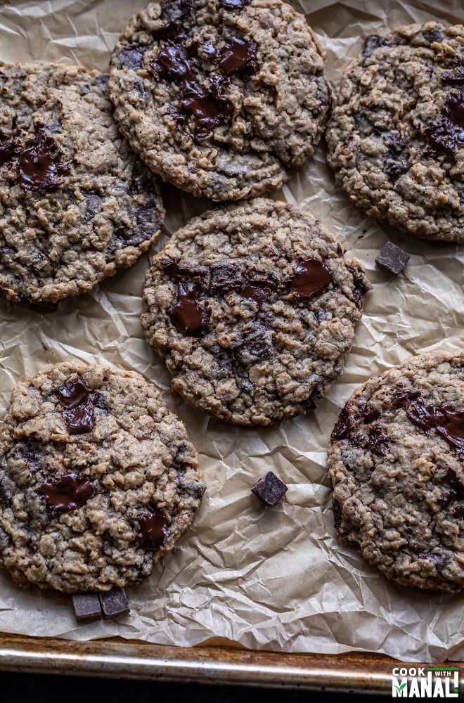 eggless oatmeal chocolate chunk cookies arranged on top of a parchment paper on a baking tray