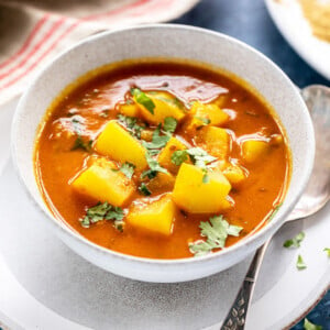 lauki curry in a white bowl with a spoon placed on the side