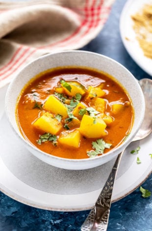 lauki curry in a white bowl with a spoon placed on the side