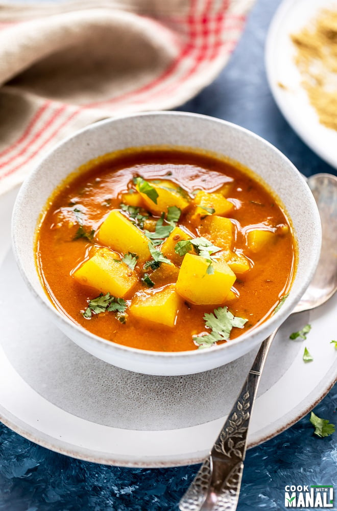 lauki curry in a white bowl with a spoon placed on the side