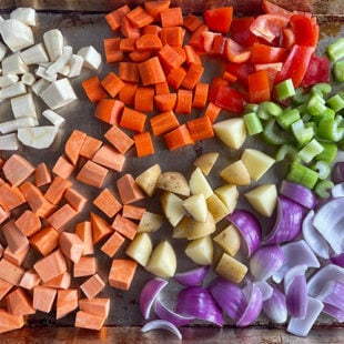 chopped sweet potatoes, red pepper, onion, potatoes, celery placed in a baking tray